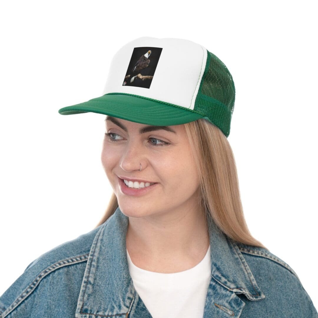Smiling woman wearing a green and white trucker hat and denim jacket.
