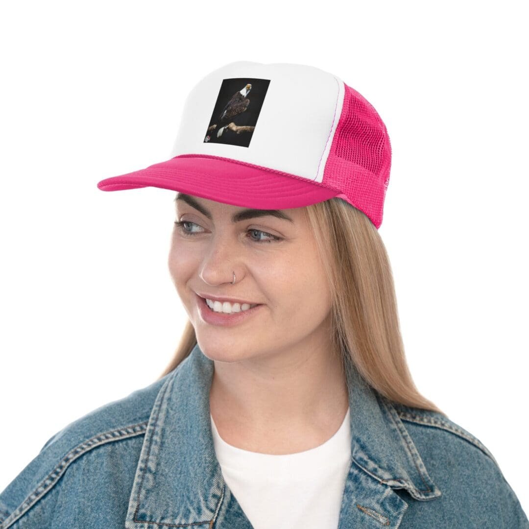 A young woman wearing a pink and white baseball cap and denim jacket, smiling.