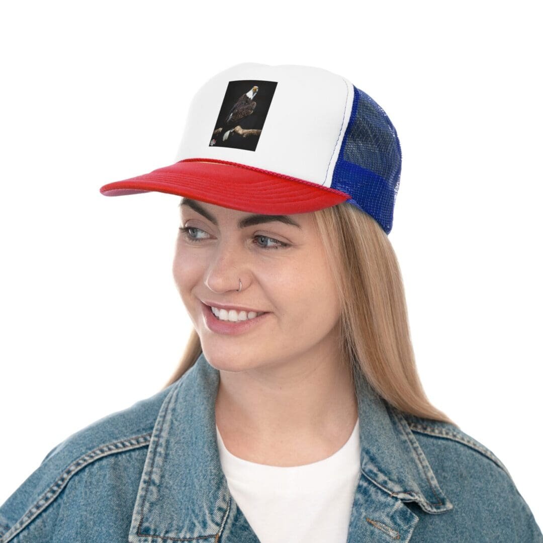 Young woman smiling wearing a red, white, and blue cap and denim jacket.